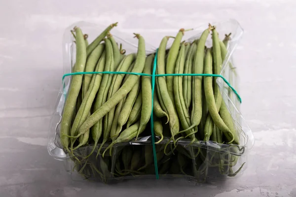 Green beans in plastic box on ceramic background — Stock Photo, Image
