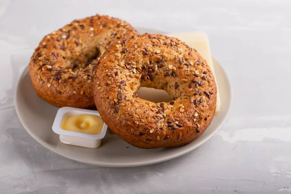 Färska bagels med smör och ost på tallrik på keramiska backgrou — Stockfoto