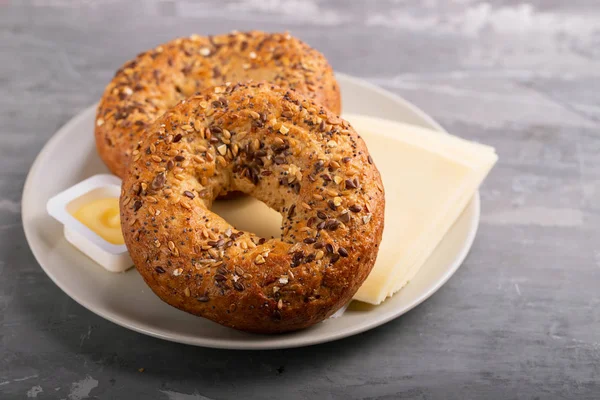 Färska bagels med smör och ost på tallrik på keramiska backgrou — Stockfoto