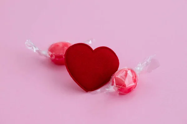 Red heart with candies on pink paper background — 스톡 사진