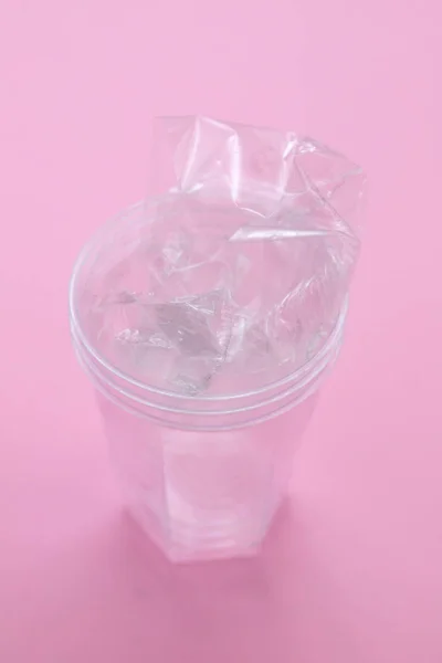 Πλαστικό γυαλί σε ροζ χάρτινο φόντο — Φωτογραφία Αρχείου