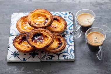 Tipik Portekiz yumurtalı tart pastel de nata ve bir fincan kahve.