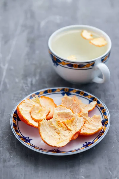 Апельсиновая кожура на тарелке и в чашке с горячей водой — стоковое фото