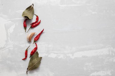 Yaprak, kırmızı biber ve seramik zemin üzerinde sarımsak.