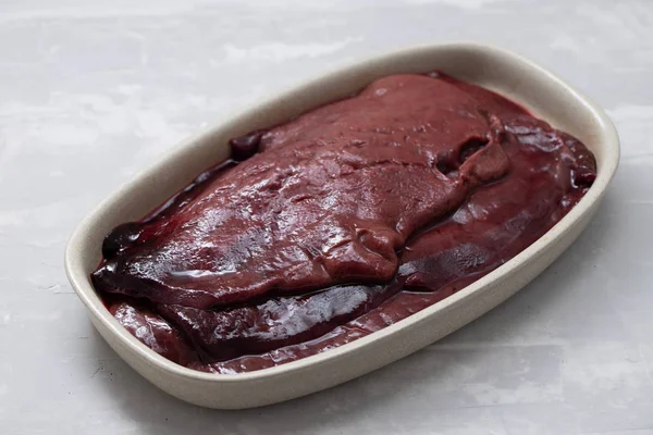 raw pork liver on dish on ceramic background