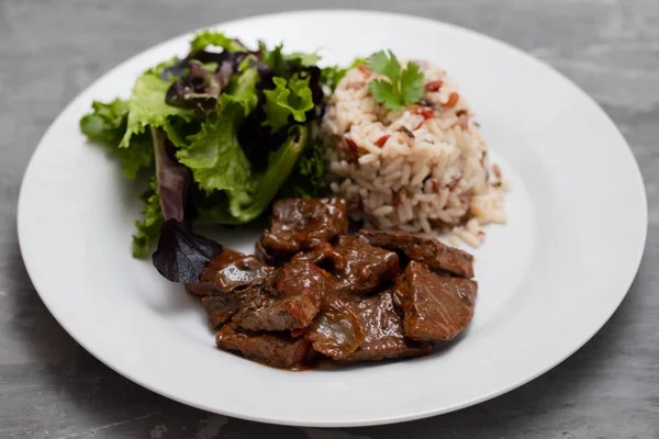 Gebratene Leber mit Salat und gekochtem Reis auf weißem Teller — Stockfoto