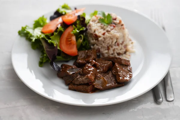 Stekt lever med sallad och kokt ris på vit tallrik — Stockfoto