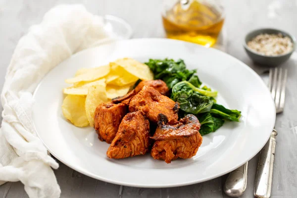 Fried meat with potato chips and greens on white plate on cerami — Stock Photo, Image