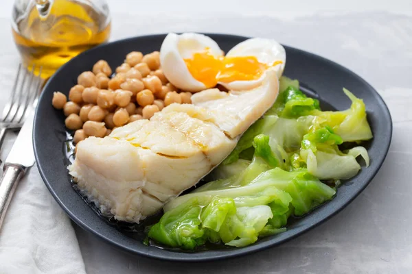 Bacalhau frito com grão de bico, ovo cozido e repolho no escuro di — Fotografia de Stock