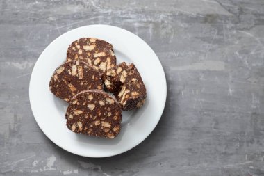 Beyaz tabakta lezzetli çikolatalı bisküvi salamı.