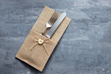 Gri seramik zemin üzerinde peçeteyle çatal ve bıçak.