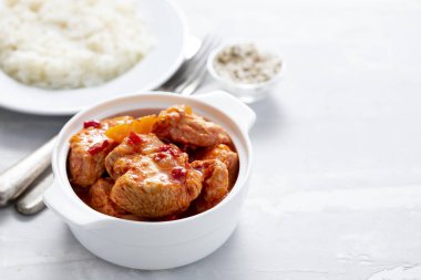 Beyaz kasede pişmiş hindi eti ve beyaz tabakta haşlanmış pirinç.