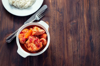 Beyaz kasede pişmiş hindi eti ve beyaz tabakta haşlanmış pirinç.