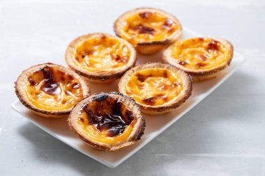 Tipik Portekiz tatlıları seramik zemin üzerinde beyaz tabak üzerine pastel de nata