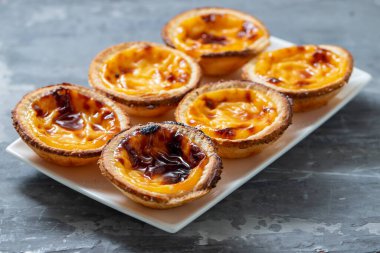Tipik Portekiz tatlıları seramik zemin üzerinde beyaz tabak üzerine pastel de nata