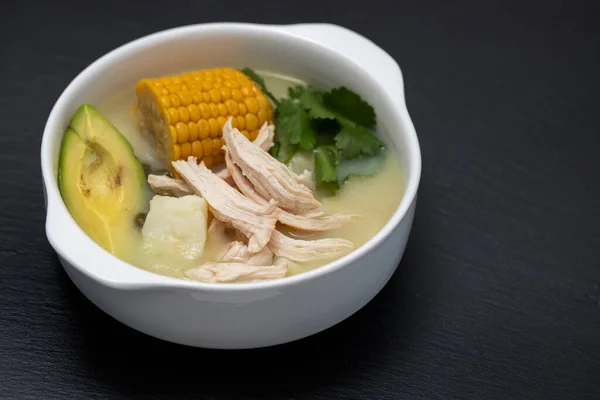 soup potato with corn and chicken in white bowl on black ceramic background