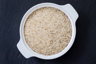 Beyaz kasede, seramik zemin üzerinde pişmemiş beyaz pirinç.