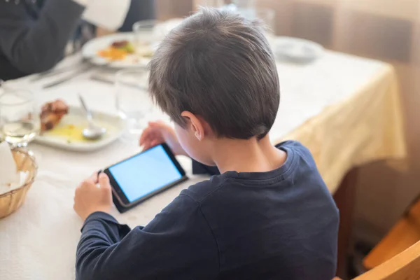 boy playing with smartphone in restaurant