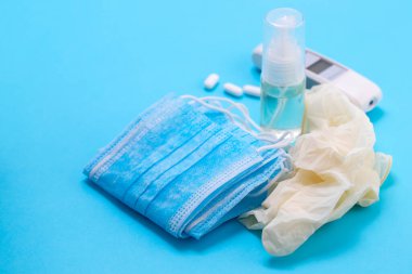 Mavi arka planda tıbbi maske, eldiven ve dezenfektan.