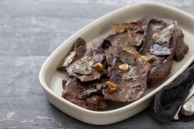 Seramik zemin üzerinde sarımsaklı kızarmış ciğer.