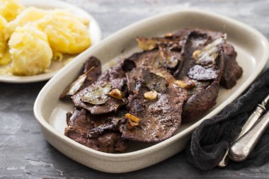 Seramik zemin üzerinde sarımsaklı kızarmış ciğer.