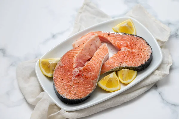 raw salmon with lemon on white dish