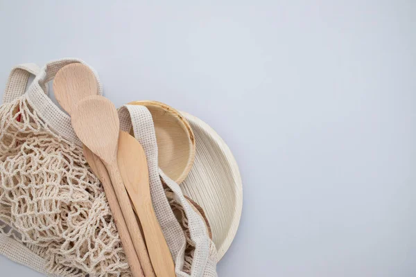 Eco-friendly utensils made of bamboo, wood and paper on gray background