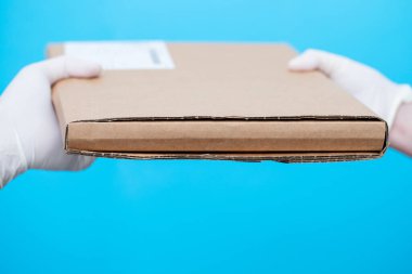 Eldivenli el mavi arka planda teslim kutusu