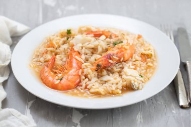 Seramik zemin üzerinde beyaz tabakta balık ve deniz ürünleri olan pirinç.