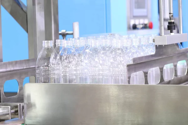 Un grupo de botellas plásticas en línea de producción esperan para llenar el agua —  Fotos de Stock