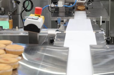 cupcake paketleme makinesi; gıda endüstrisi geri planda ;