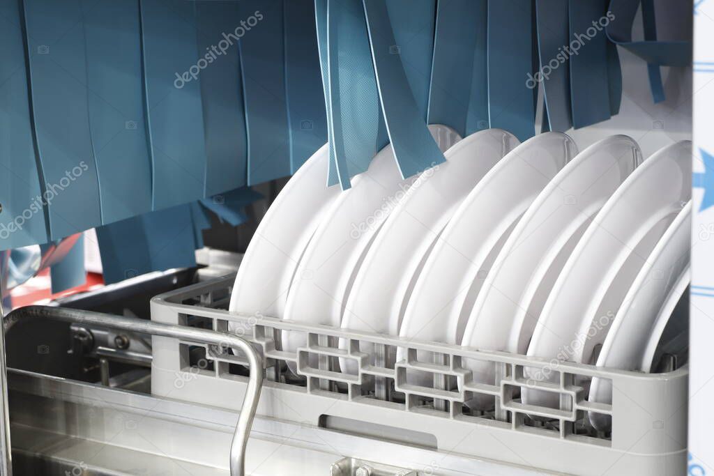The automatic dishwasher with white clean dishes in basket .For restaurant. Business industrial background