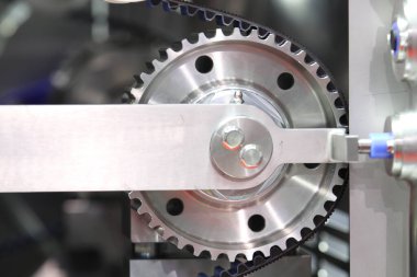 NUGGETS EAT OTOMATIC makinesindeki dişli davulunun dönüşünü senkronize eden siyah zamanlama kemeri; endüstriyel mühendislik arka planı