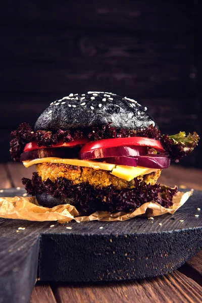 Hambúrguer caseiro. Grão de bico preto vegetariano com uma costeleta, tomate, queijo, alface escura e cebola roxa na mesa de madeira rústica. Violeta tonificada — Fotografia de Stock