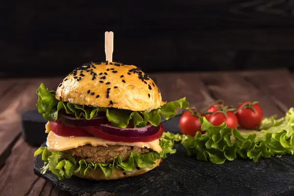 Hausgemachter vegetarischer Burger mit Schnitzel, Tomate, Käse, grünem Salat und lila Zwiebeln auf dunklem Holzgrund — Stockfoto