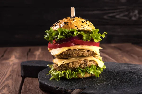 Hausgemachter vegetarischer Doppel-Burger mit zwei Schnitzeln, Tomate, Käse, grünem Salat und lila Zwiebeln auf dunklem Holzgrund — Stockfoto