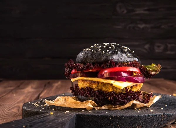 Nahaufnahme auf Black Burger gefüllt mit gegrillten Zwiebeln, Tomatenscheiben und Salat — Stockfoto