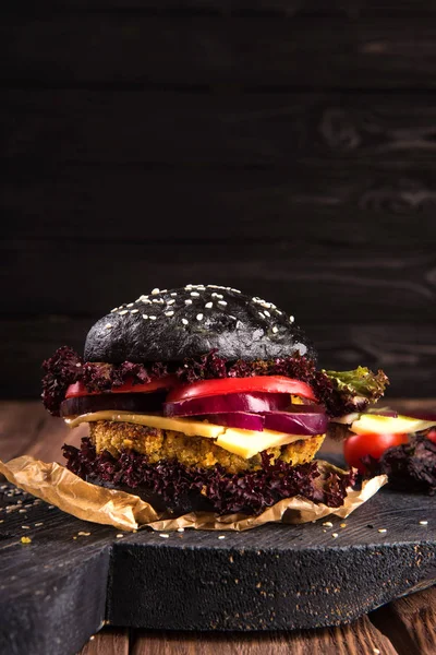 Nahaufnahme von hausgemachten Rindfleisch-Burgern mit Salat und Mayonnaise, serviert auf einem kleinen Holzschneidebrett. dunkler Hintergrund — Stockfoto