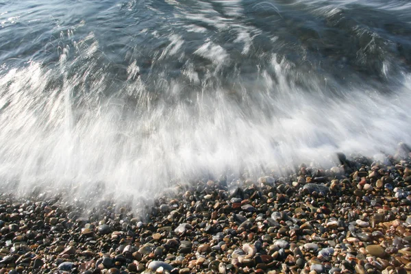 Espuma de olas de choque en la playa de piedra — Foto de Stock