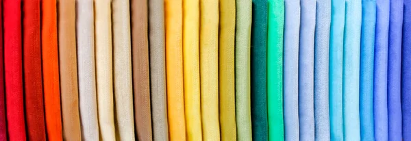 Rainbow clothes background. Pile of bright folded clothes.