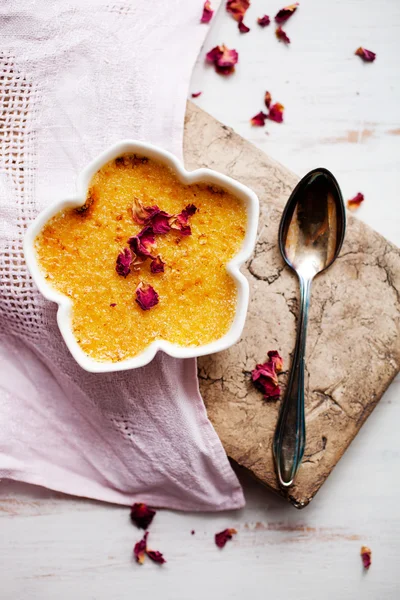 Creme brulee with edble pink roses — Stockfoto