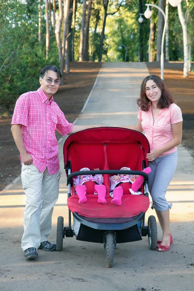 Young parents and their two little children in a twin stroller — Stock Photo, Image