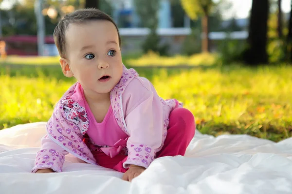 Schattig baby meisje zitten op het gras in het park — Stockfoto