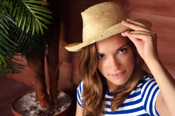 Loira senhora segurando chapéu de palha e sentado perto de casa de madeira em s — Fotografia de Stock