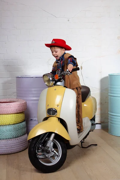 Маленький мальчик в костюме ковбоя на скутере — стоковое фото