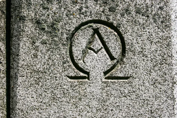 Alpha omega symbol carved in grey granite stone