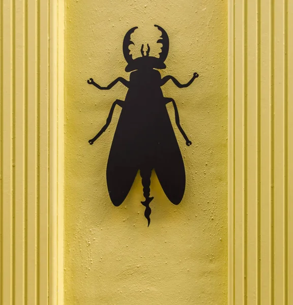 Black metal beetle on a stylish yellow facade of the building, w — Stock Photo, Image