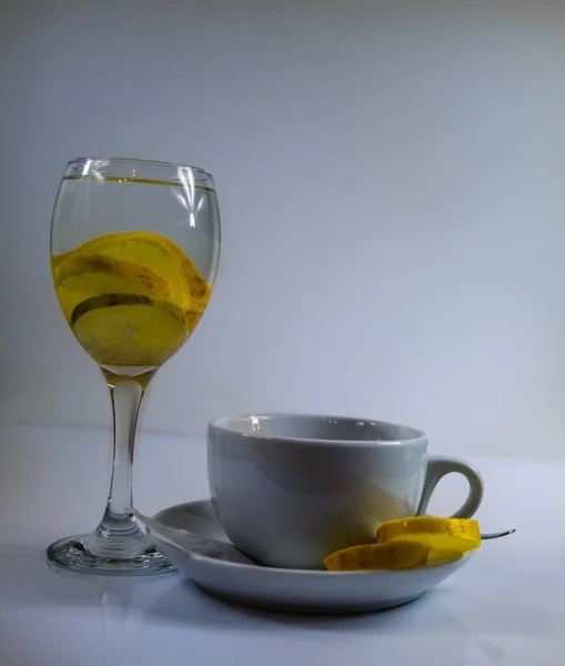 Copo de água com limão e uma grande xícara de chá e limão — Fotografia de Stock
