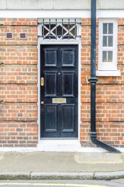 Dışarıda girişinde bir tuğla bina, şık siyah bir kapı,