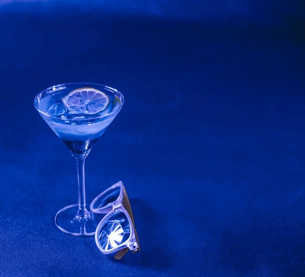 Blue background, mixed drink, lemon, martini glass, yellow sungl — Stock Photo, Image